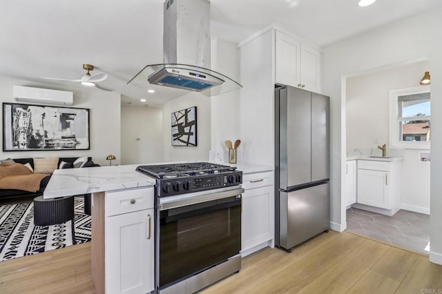 8450 Dallas St, La Mesa, CA 91942 - kitchen featuring appliances with stainless steel finishes, island exhaust hood, a wall unit AC, light wood-style flooring, and light stone counters