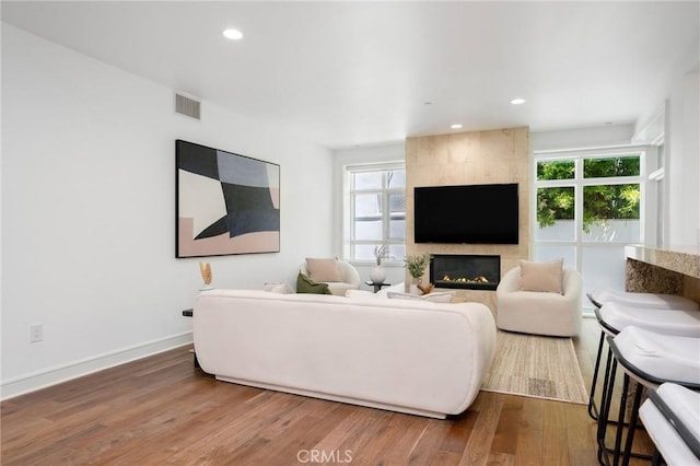 447 N Doheny Dr Unit 104, Beverly Hills, CA 90210 - living area featuring plenty of natural light, wood finished floors, a tiled fireplace, and recessed lighting