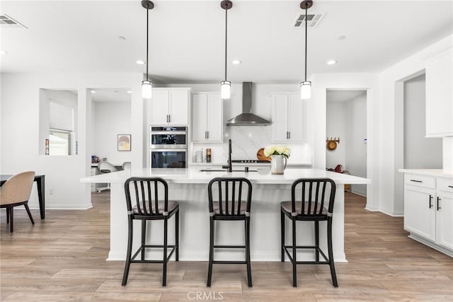 32886 Birchall Ct, Winchester, CA 92596 - kitchen with wall chimney exhaust hood, double oven, light countertops, a breakfast bar, and recessed lighting