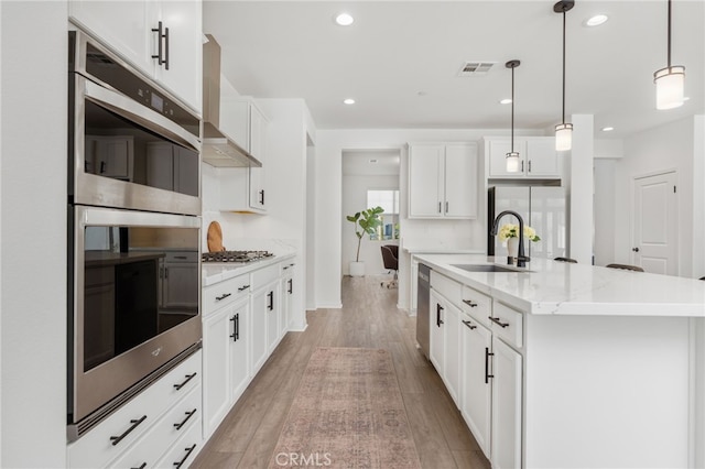 32886 Birchall Ct, Winchester, CA 92596 - kitchen with appliances with stainless steel finishes, light wood finished floors, a center island with sink, recessed lighting, and hanging light fixtures