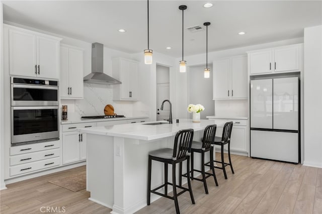 32886 Birchall Ct, Winchester, CA 92596 - kitchen featuring freestanding refrigerator, wall chimney range hood, stainless steel double oven, light wood finished floors, and white cabinets