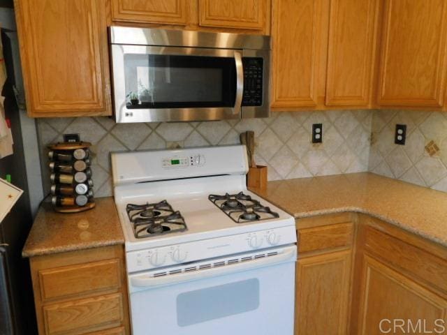1203 Buckwheat Trl, Campo, CA 91906 - kitchen featuring white gas stove, stainless steel microwave, and backsplash