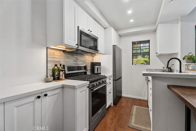 1046 Calle Del Cerro Unit 408, San Clemente, CA 92672 - kitchen featuring appliances with stainless steel finishes, dark wood-style flooring, decorative backsplash, white cabinetry, and recessed lighting
