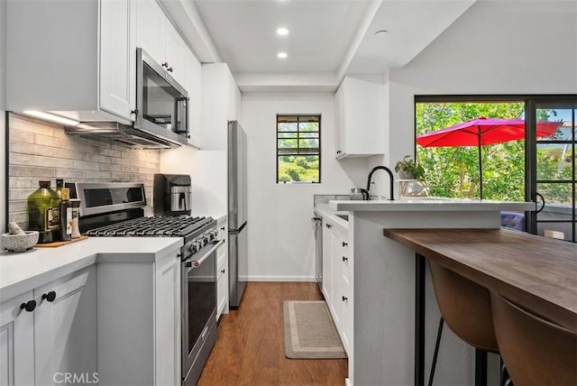 1046 Calle Del Cerro Unit 408, San Clemente, CA 92672 - kitchen featuring appliances with stainless steel finishes, dark wood finished floors, recessed lighting, white cabinets, and decorative backsplash