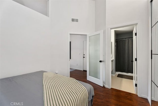 1046 Calle Del Cerro Unit 408, San Clemente, CA 92672 - bedroom featuring wood finished floors, a towering ceiling, and connected bathroom