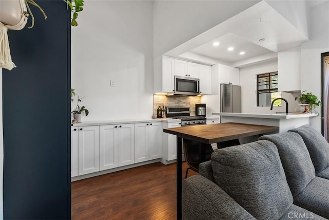 1046 Calle Del Cerro Unit 408, San Clemente, CA 92672 - kitchen with stainless steel appliances, dark wood-style flooring, tasteful backsplash, white cabinets, and recessed lighting