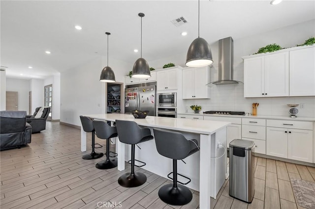 1938 N Frontier St, Hanford, CA 93230 - kitchen featuring wall chimney range hood, built in appliances, wood finish floors, tasteful backsplash, and recessed lighting