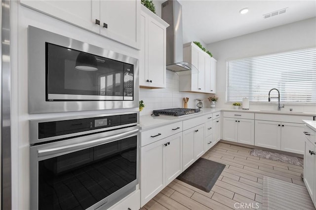 1938 N Frontier St, Hanford, CA 93230 - kitchen featuring appliances with stainless steel finishes, wall chimney range hood, light countertops, white cabinets, and recessed lighting
