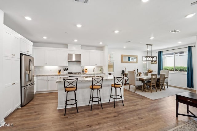 1979 Tangelo Way, Santa Paula, CA 93060 - kitchen featuring appliances with stainless steel finishes, under cabinet range hood, a center island with sink, white cabinetry, and light wood-type flooring