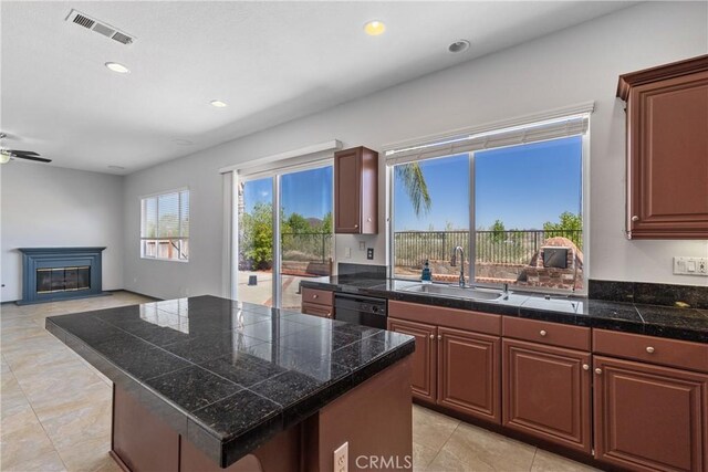 32522 Safflower St, Winchester, CA 92596 - kitchen with tile counters, a glass covered fireplace, black dishwasher, recessed lighting, and a kitchen island