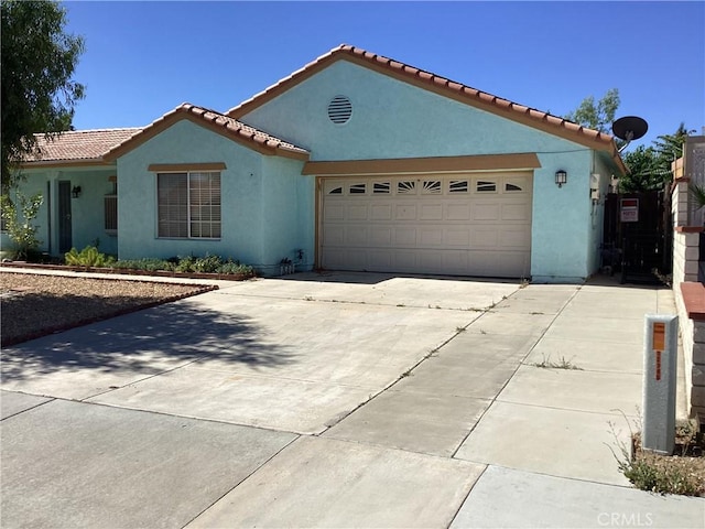 13489 Buggy Whip Ct, Victorville, CA 92392 - mediterranean / spanish home with concrete driveway, stucco siding, an attached garage, and a tile roof