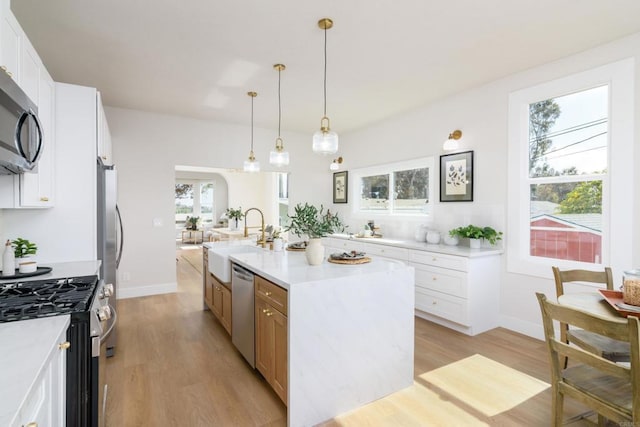 7284 W Point Ave, La Mesa, CA 91942 - kitchen with appliances with stainless steel finishes, light wood-style floors, a center island with sink, and light countertops