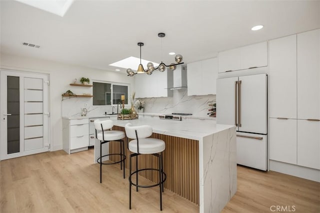 3253 San Amadeo Unit P, Laguna Woods, CA 92637 - kitchen featuring white appliances, wall chimney range hood, a skylight, open shelves, and white cabinetry