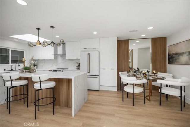 3253 San Amadeo Unit P, Laguna Woods, CA 92637 - kitchen featuring high end fridge, white cabinets, backsplash, modern cabinets, and light wood finished floors