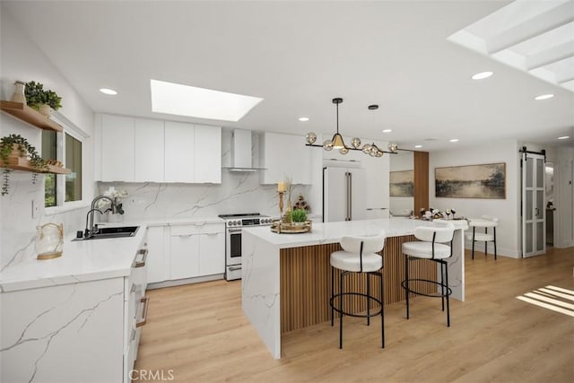 3253 San Amadeo Unit P, Laguna Woods, CA 92637 - kitchen with high quality stove, a skylight, wall chimney range hood, recessed lighting, and tasteful backsplash