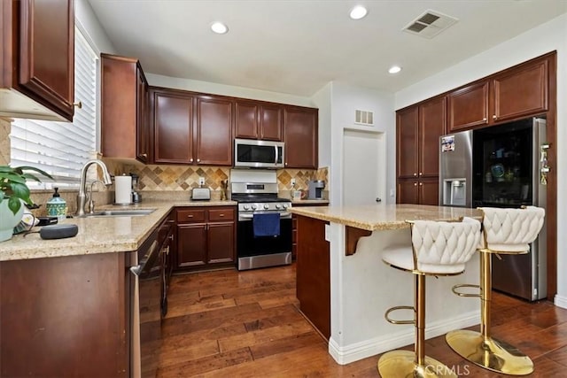 10349 Cooks Dr Unit 2, Rancho Cucamonga, CA 91730 - kitchen featuring appliances with stainless steel finishes, dark wood-style flooring, light stone counters, tasteful backsplash, and a breakfast bar area