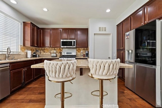 10349 Cooks Dr Unit 2, Rancho Cucamonga, CA 91730 - kitchen featuring appliances with stainless steel finishes, dark wood-type flooring, tasteful backsplash, a center island, and light stone countertops