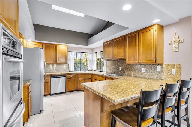 1549 Hillcrest Dr, Pomona, CA 91768 - kitchen with stainless steel appliances, a raised ceiling, a peninsula, brown cabinets, and light stone countertops