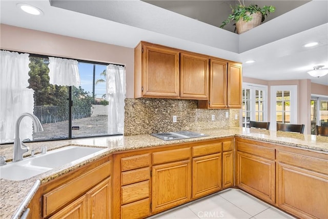 1549 Hillcrest Dr, Pomona, CA 91768 - kitchen with black electric stovetop, light stone countertops, decorative backsplash, brown cabinetry, and recessed lighting