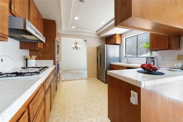 6157 Hillary Ct, Riverside, CA 92506 - kitchen with under cabinet range hood, tile countertops, stainless steel fridge, white gas stovetop, and light floors