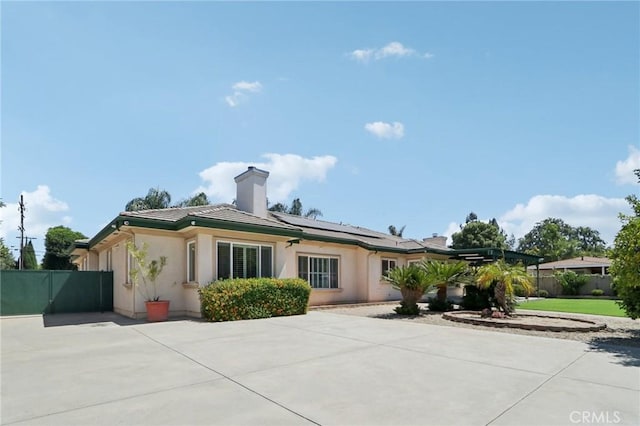 16860 Rayen St, Northridge, CA 91343 - back of house featuring solar panels, stucco siding, and a chimney