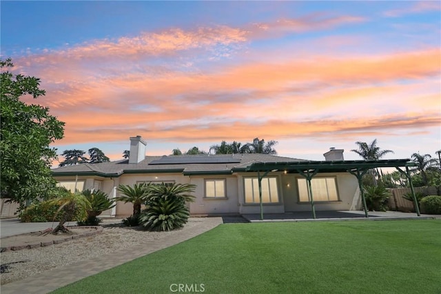 16860 Rayen St, Northridge, CA 91343 - back of property at dusk featuring roof mounted solar panels, a chimney, and stucco siding