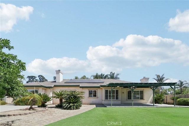 16860 Rayen St, Northridge, CA 91343 - rear view of property with roof mounted solar panels, stucco siding, and a chimney