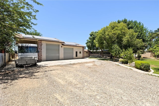 921 Christian Ave, Bakersfield, CA 93314 - view of front facade with solar panels, gravel driveway, an attached garage, and stucco siding