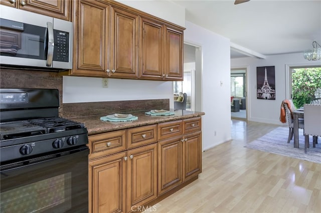 4931 Saint Andrews Ave, Buena Park, CA 90621 - kitchen featuring black gas range oven, stainless steel microwave, brown cabinets, and light wood-style flooring