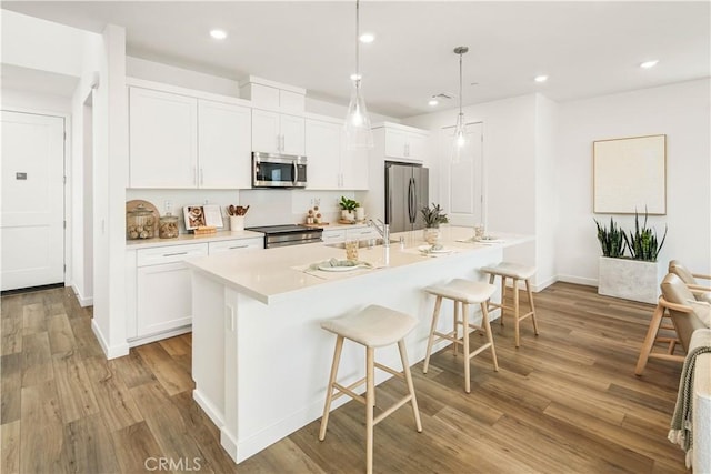 4830 Arroyo Run, Moorpark, CA 93021 - kitchen featuring appliances with stainless steel finishes, white cabinetry, a kitchen island with sink, a breakfast bar, and light wood finished floors