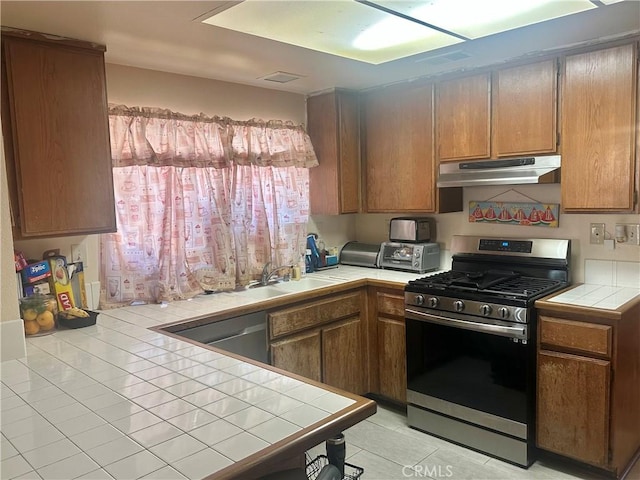 3539 Castaic, Riverside, CA 92501 - kitchen featuring stainless steel appliances, under cabinet range hood, tile counters, light tile patterned floors, and brown cabinets