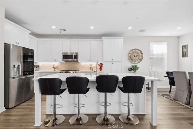 28709 Wildflower, Castaic, CA 91384 - kitchen featuring appliances with stainless steel finishes, light countertops, white cabinets, a kitchen island with sink, and decorative backsplash