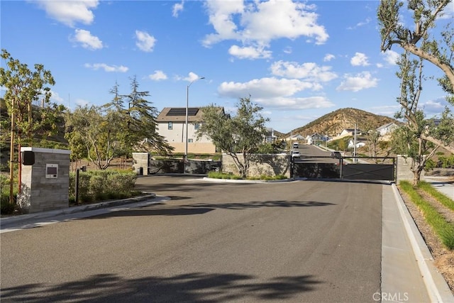28709 Wildflower, Castaic, CA 91384 - view of asphalt road with a gate, curbs, a gated entry, street lights, and a mountain view