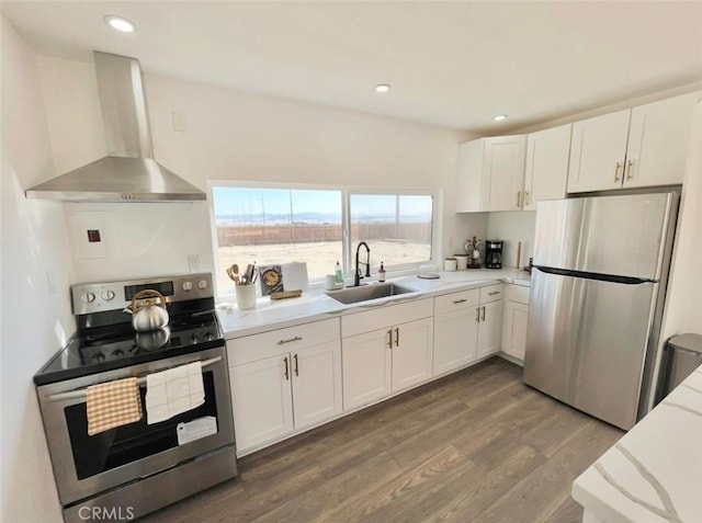 3191 Pearl Springs Ave Unit 29, Palms, CA 92277 - kitchen with stainless steel appliances, wall chimney range hood, wood finished floors, white cabinetry, and recessed lighting
