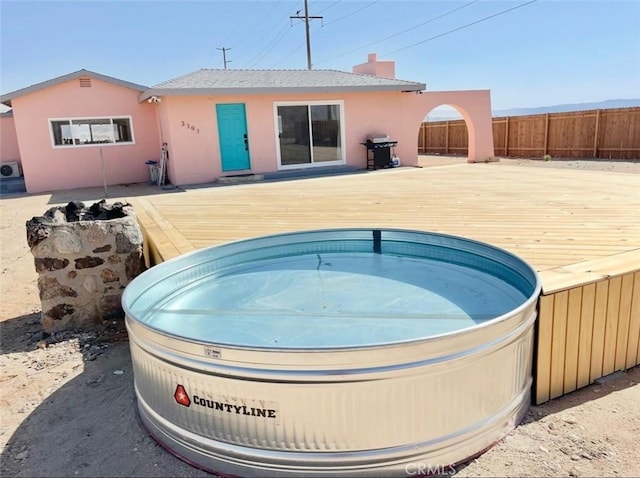 3191 Pearl Springs Ave Unit 29, Palms, CA 92277 - rear view of property featuring a jacuzzi, a wooden deck, a chimney, and stucco siding