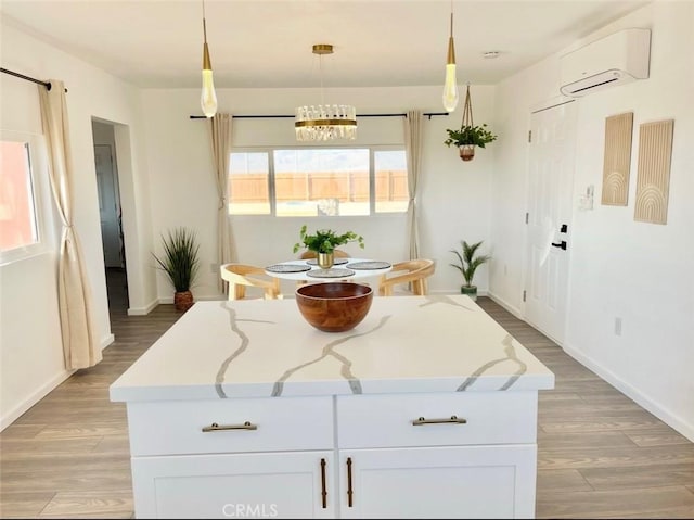 3191 Pearl Springs Ave Unit 29, Palms, CA 92277 - kitchen with a wall mounted AC, light wood-type flooring, white cabinets, pendant lighting, and a center island