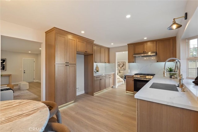7372 Brian Ln, La Palma, CA 90623 - kitchen with stainless steel range with gas cooktop, under cabinet range hood, recessed lighting, tasteful backsplash, and light wood-style flooring