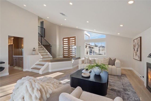 7372 Brian Ln, La Palma, CA 90623 - living area with wood finished floors, recessed lighting, high vaulted ceiling, stairway, and a glass covered fireplace