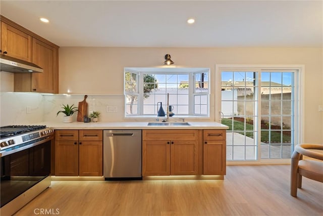 7372 Brian Ln, La Palma, CA 90623 - kitchen with stainless steel appliances, under cabinet range hood, light wood finished floors, brown cabinetry, and backsplash