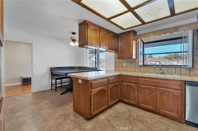 19055 Seaforth St, Hesperia, CA 92345 - kitchen with stainless steel dishwasher, brown cabinetry, backsplash, and tile countertops