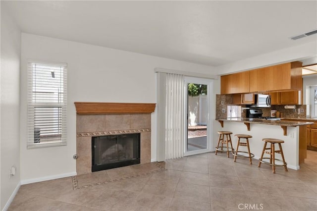 1850 Coolidge St, Corona, CA 92879 - kitchen featuring range, a kitchen breakfast bar, brown cabinets, tasteful backsplash, and stainless steel microwave
