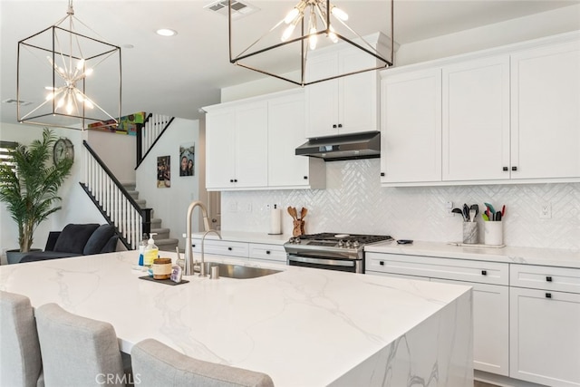 2227 Melogold Way, Corona, CA 92883 - kitchen with stainless steel gas range, a chandelier, under cabinet range hood, backsplash, and recessed lighting