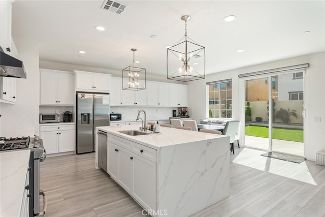 2227 Melogold Way, Corona, CA 92883 - kitchen featuring stainless steel appliances, a chandelier, decorative backsplash, white cabinetry, and an island with sink
