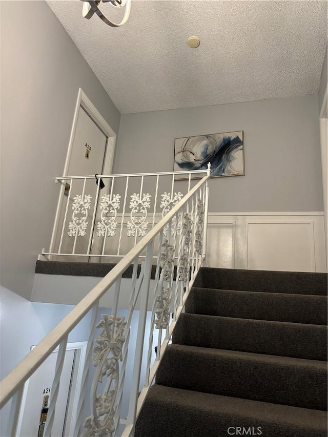 1521 S Pomona Ave Unit A23, Fullerton, CA 92832 - staircase with a textured ceiling, wainscoting, and a decorative wall