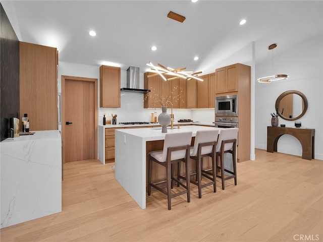 24100 Philiprimm St, Woodland Hills, CA 91367 - kitchen with stainless steel appliances, wall chimney exhaust hood, light wood finished floors, decorative backsplash, and pendant lighting