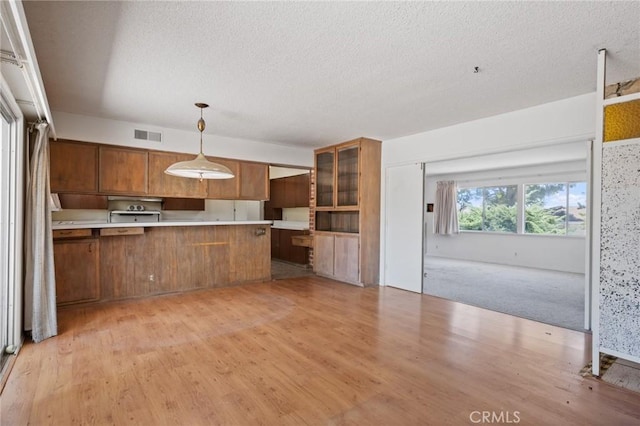 8 Coveview Dr, Rancho Palos Verdes, CA 90275 - kitchen featuring brown cabinets, a textured ceiling, light wood-type flooring, light countertops, and a peninsula