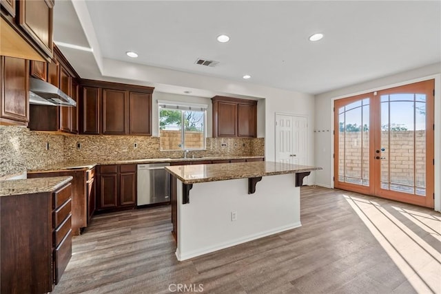 27132 Golden Field Ct, Moreno Valley, CA 92555 - kitchen with stainless steel dishwasher, under cabinet range hood, wood finished floors, a breakfast bar, and recessed lighting
