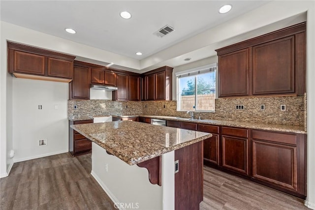 27132 Golden Field Ct, Moreno Valley, CA 92555 - kitchen with dark wood finished floors, light stone countertops, a center island, decorative backsplash, and recessed lighting