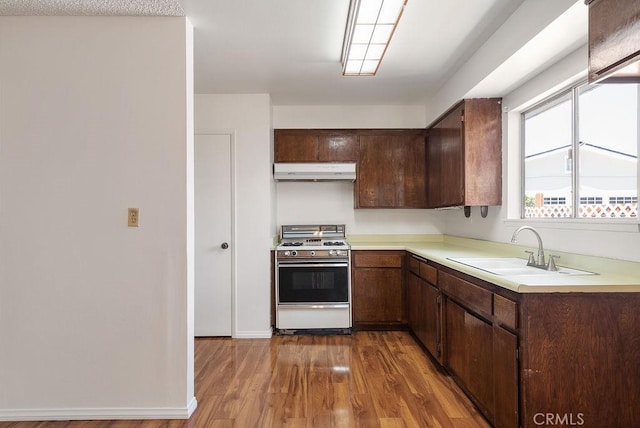 207 N Pasadena Ave, Azusa, CA 91702 - kitchen featuring white gas range, under cabinet range hood, light wood-type flooring, light countertops, and dark brown cabinetry