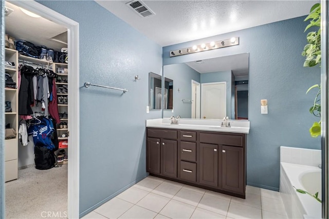2322 Carolyn Dr, Palmdale, CA 93551 - full bathroom featuring double vanity, a bath, a textured wall, a walk in closet, and a textured ceiling